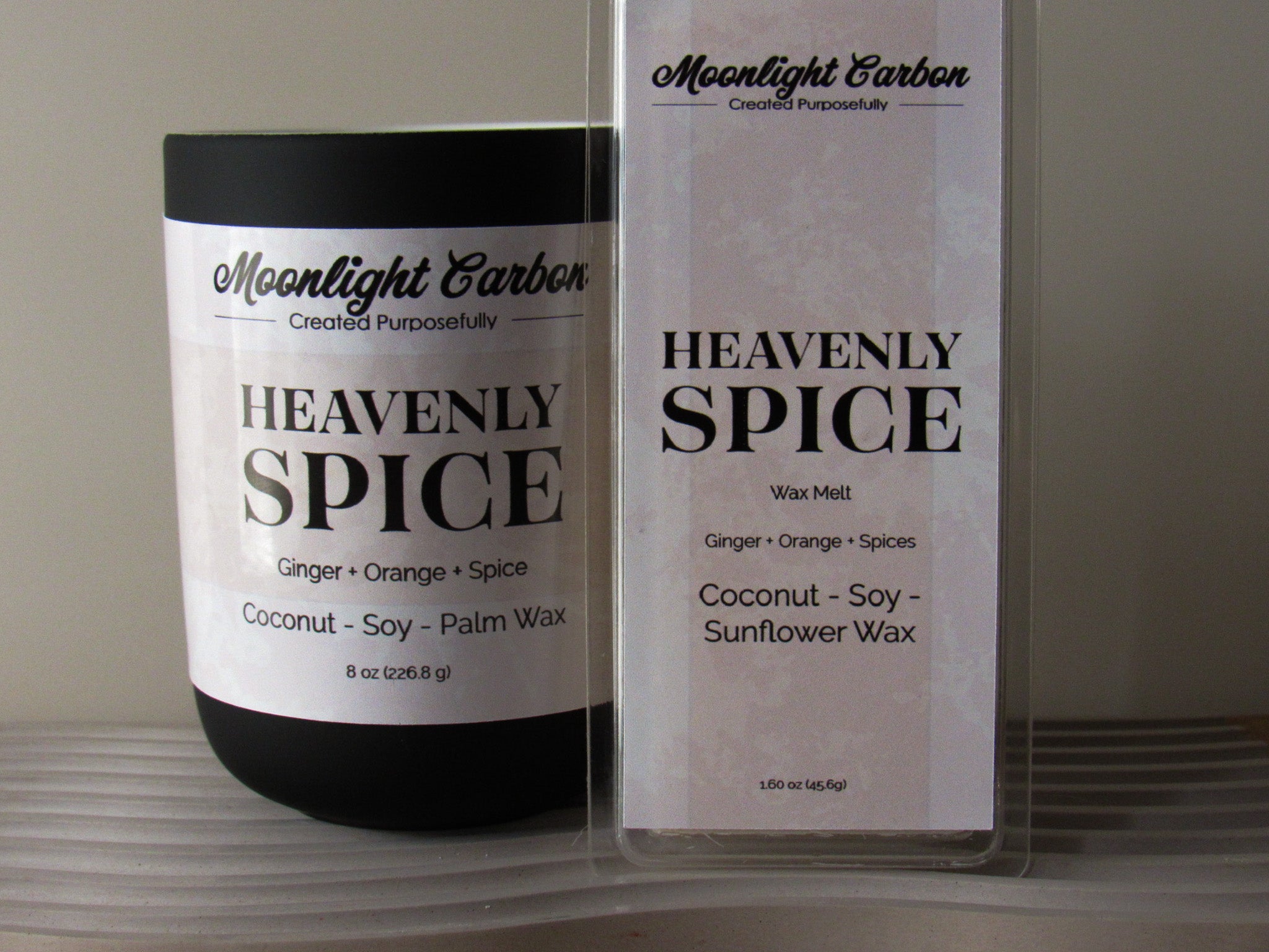 Coconut-soy wax candle and wax melt labeled 'Heavenly Spice' by Moonlight Carbon on a neutral background. Fragrance notes include ginger, blood orange, and spice. Also the wax melt pair.