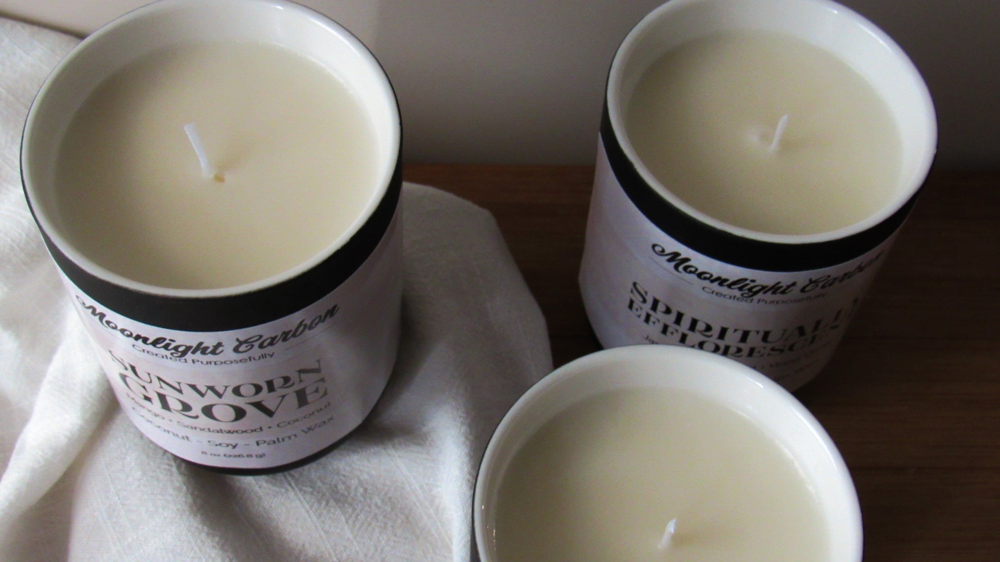 Three coconut soy candles with labels on a textured surface