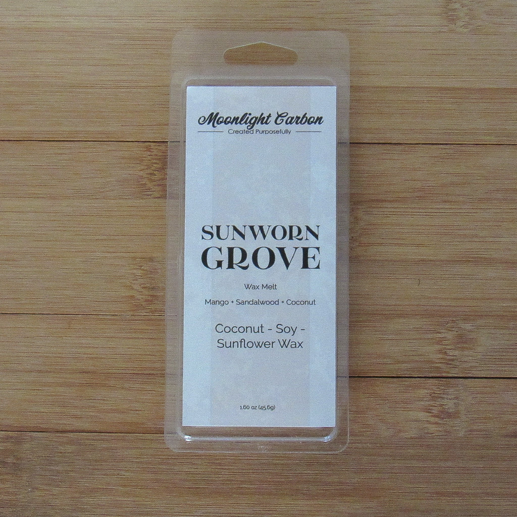 Wax melt package labeled 'Sunworn Grove' on a wooden surface. Fragrance notes include mango, coconut, and sandalwood.