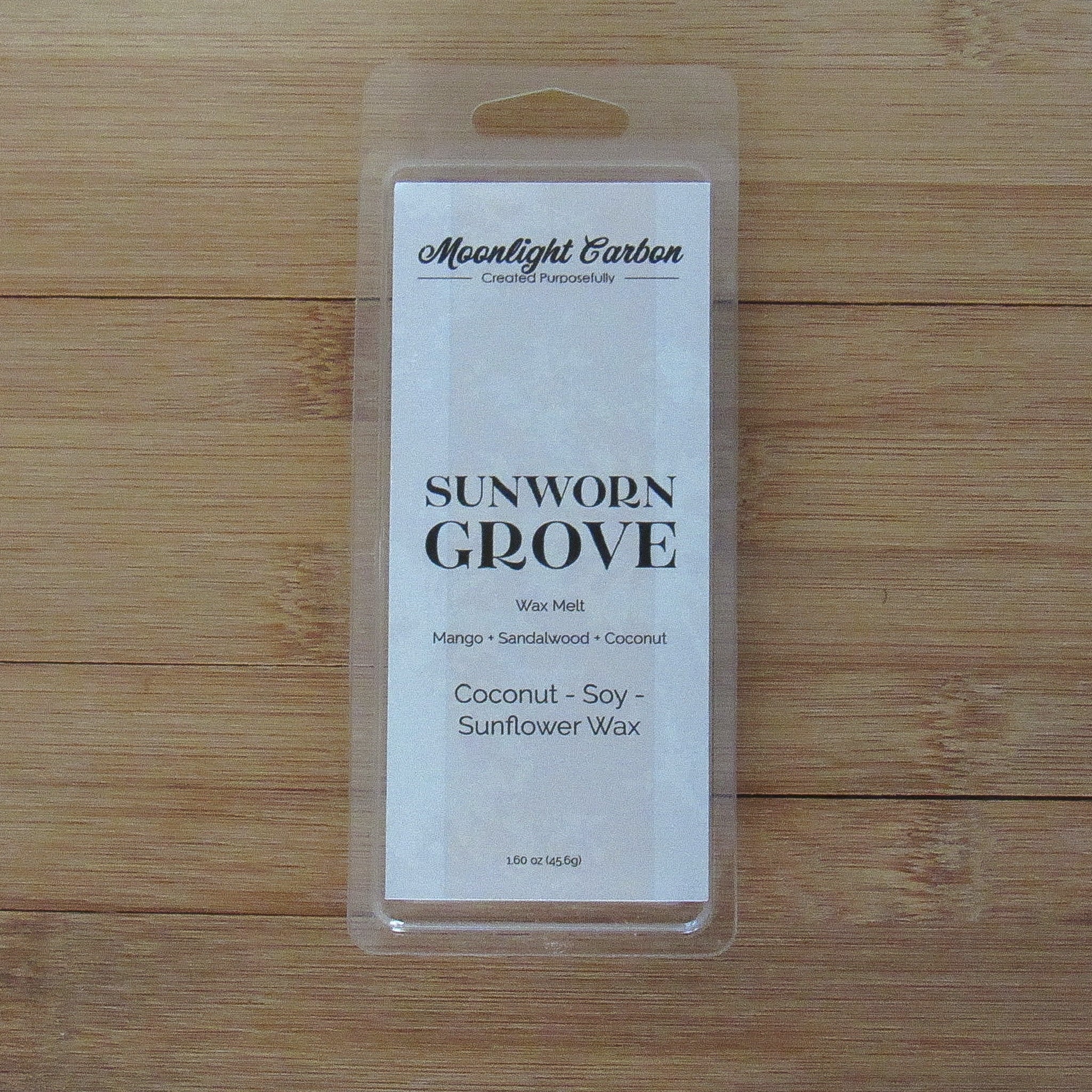 Wax melt package labeled 'Sunworn Grove' on a wooden surface. Fragrance notes include mango, coconut, and sandalwood.