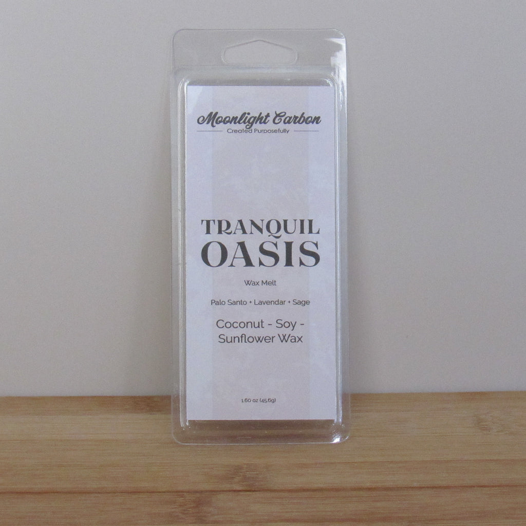 Packaged product labeled 'Tranquil Oasis' on a wooden surface with a neutral background. Fragrance notes include palo santo, lavender, and sage.