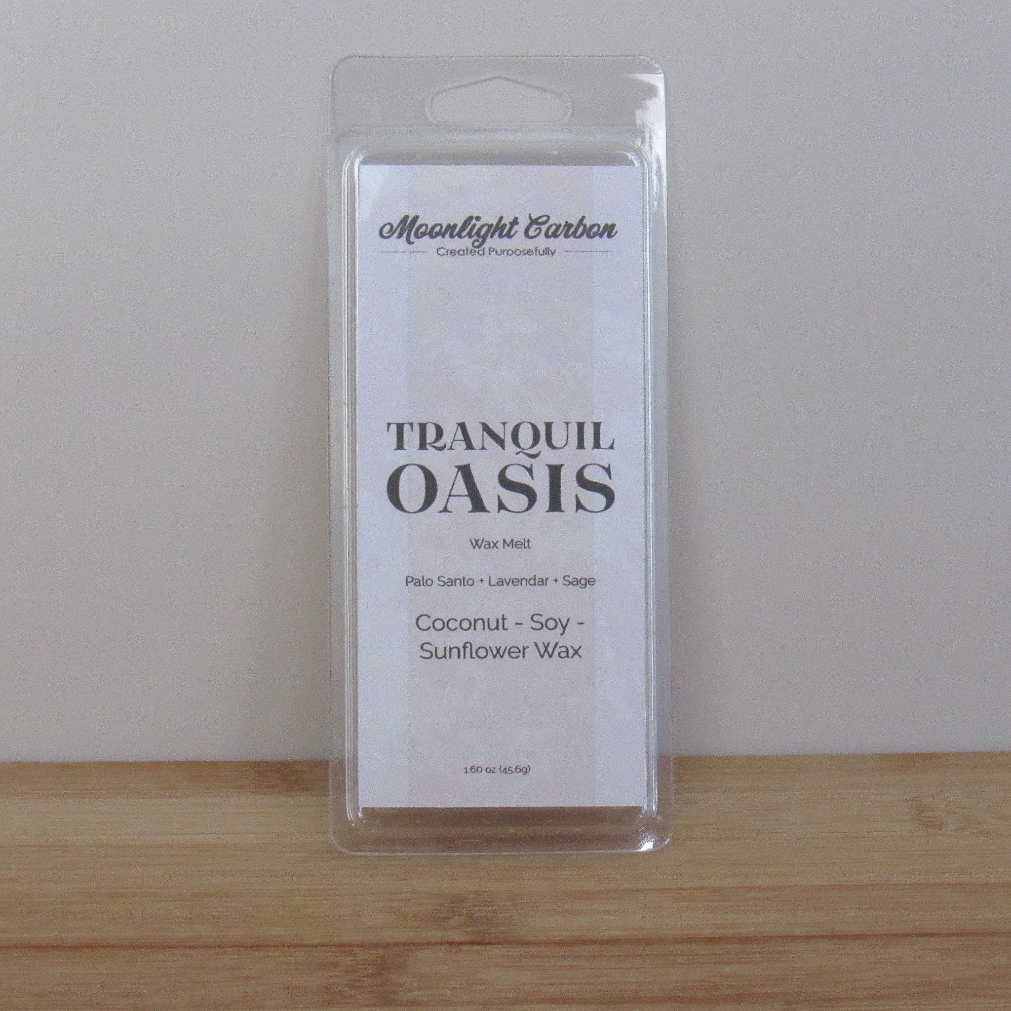 Packaged product labeled 'Tranquil Oasis' on a wooden surface with a neutral background. Fragrance notes include palo santo, lavender, and sage.