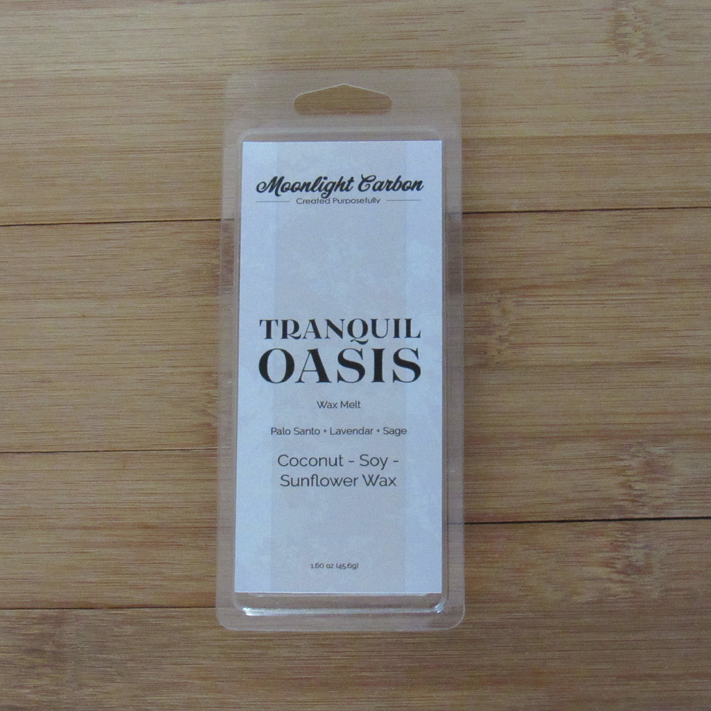 Packaged candle labeled 'Tranquil Oasis' on a wooden surface. fragrance notes include palo santo, lavender, and sage.