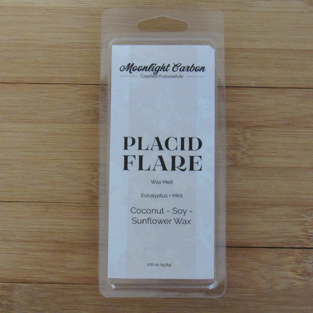 Packaged wax melt labeled 'Placid Flare' by Moonlight Carbon on a wooden surface. Fragrance notes include eucalyptus and mint.