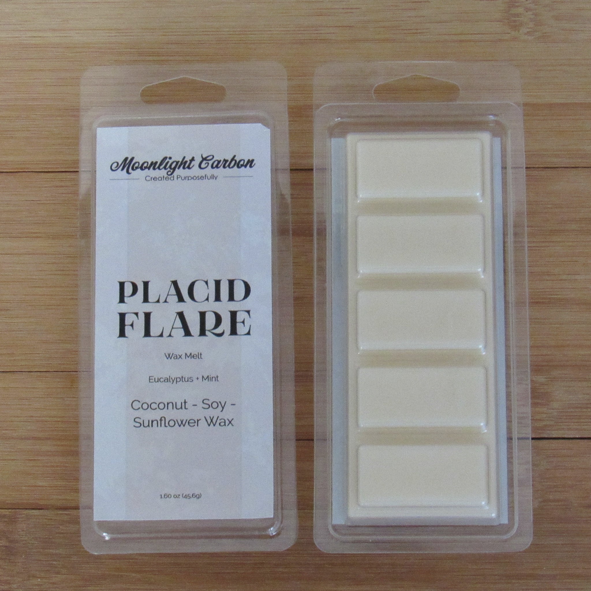 Wax melts in packaging with 'Moonlight Carbon' label on a wooden surface. Shows back of packaging with wax melts divided into 5 parts.