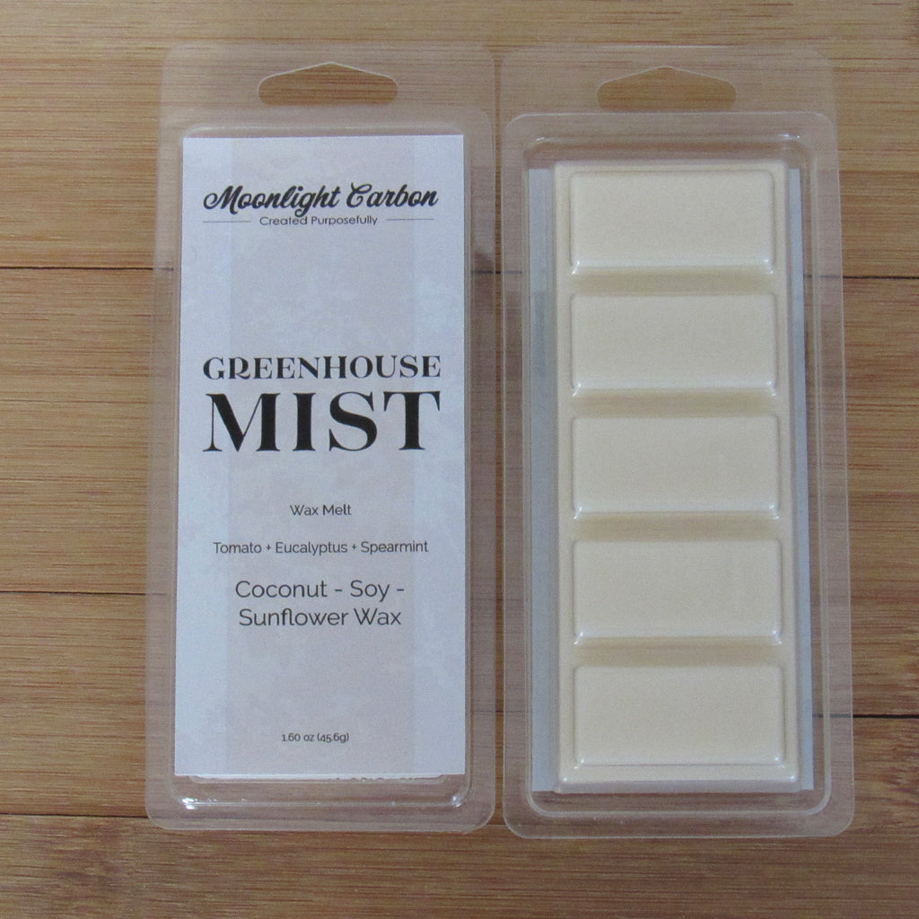 Wax melt packaging with 'Greenhouse Mist' label on a wooden surface. Show back of packaging with wax melts divided into 5 parts.