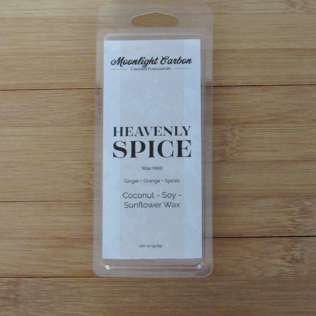 Packaging of 'Heavenly Spice' wax melt on a wooden surface. Fragrance notes include ginger, orange, and spices.