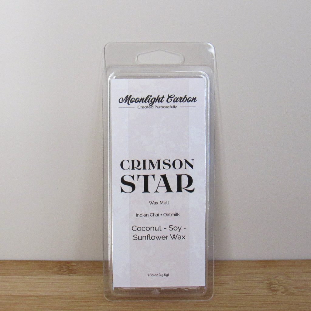 Packaged wax melt labeled 'Crimson Star' on a wooden surface with a neutral background. Fragrance notes include Indian chai and Oat milk.