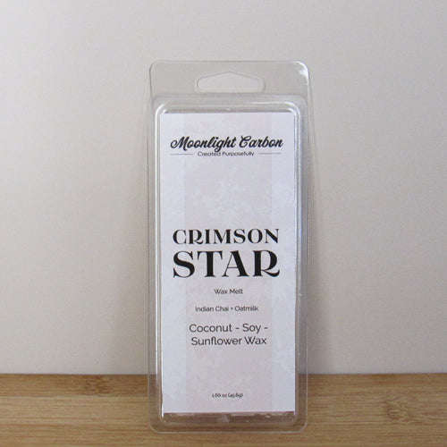 Packaged wax melt labeled 'Crimson Star' on a wooden surface with a neutral background. Fragrance notes include Indian chai and Oat milk.