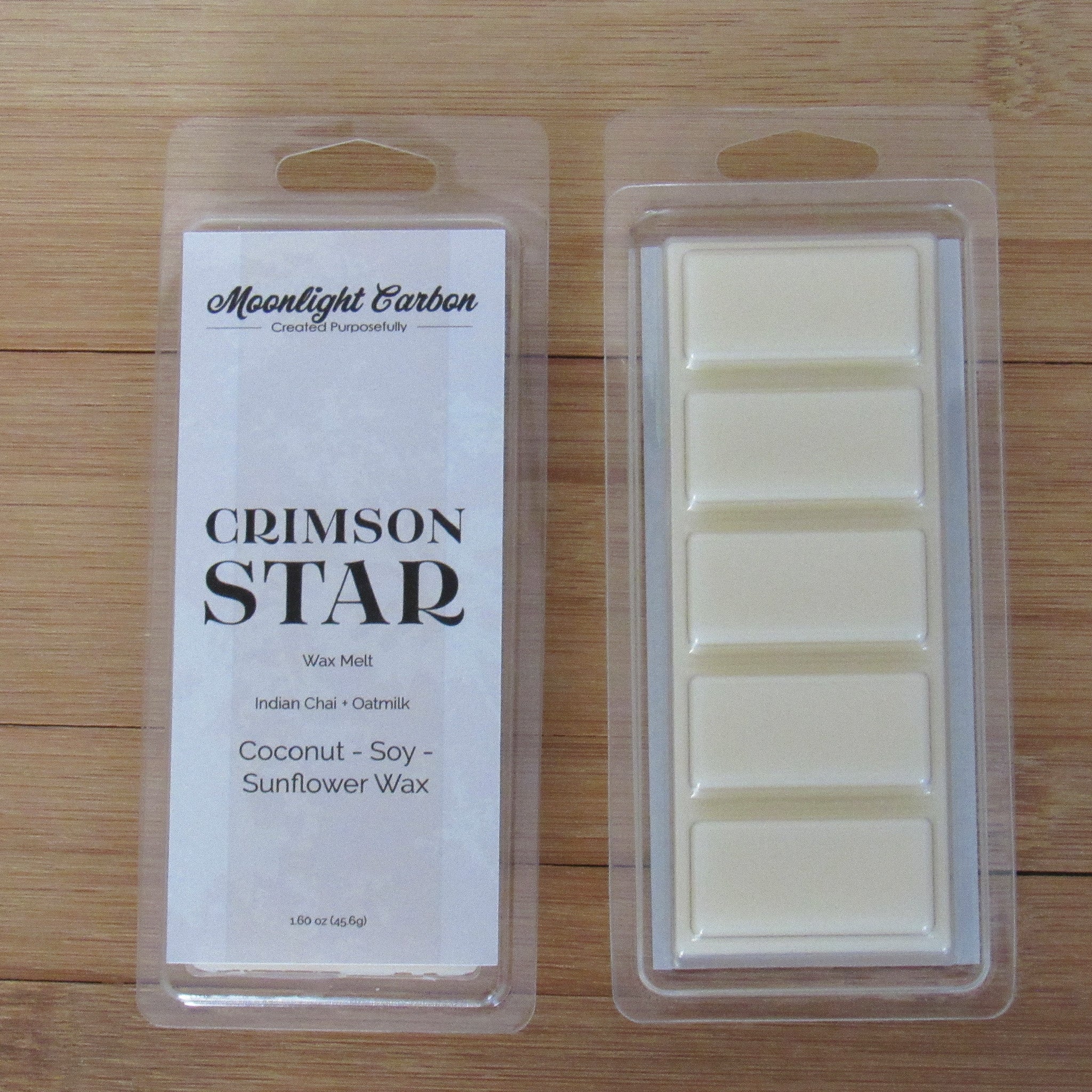 Wax melts in packaging with 'Moonlight Carbon' branding on a wooden surface. Shows back of packaging which displays wax melts able to be broken into 5 pieces.