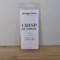 Packaged wax melt labeled 'Crisp Sunrise' by Moonlight Carbon on a wooden surface with a white background. Fragrance notes include fresh laundry.