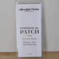 Wax melt package labeled 'Whimsical Patch' with branding on a plain background. Fragrance notes include herbal garden and strawberries. 