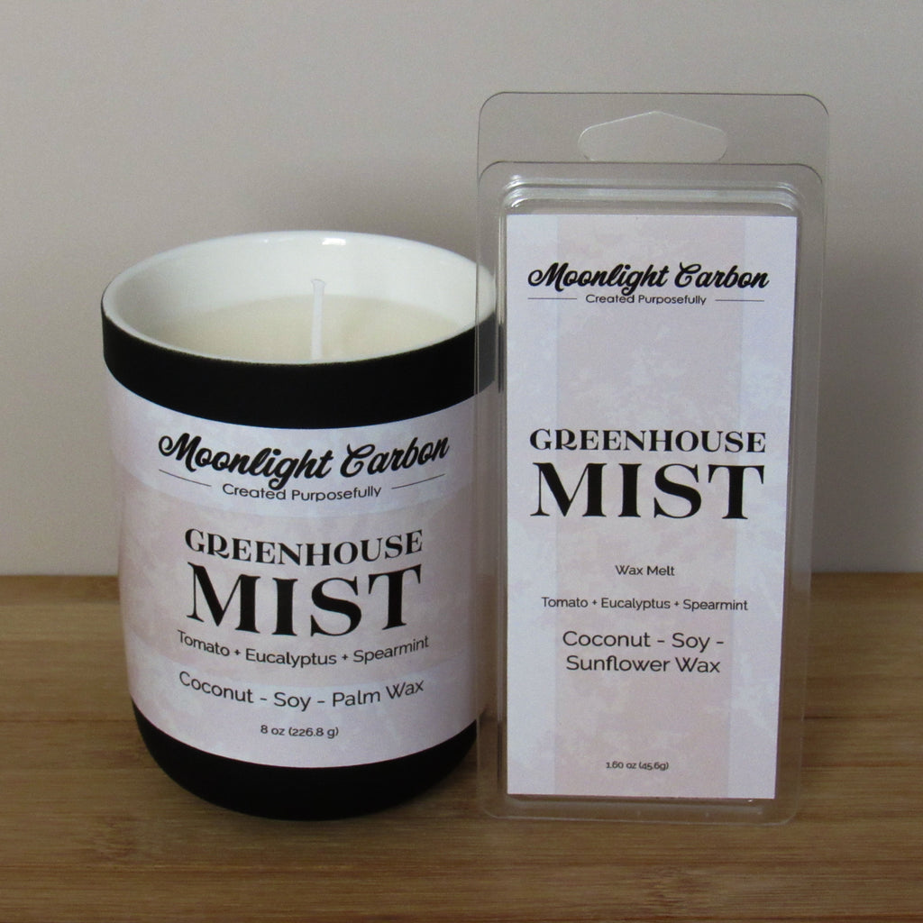 Candle and wax melt packaging of 'Greenhouse Mist' by Moonlight Carbon on a wooden surface.