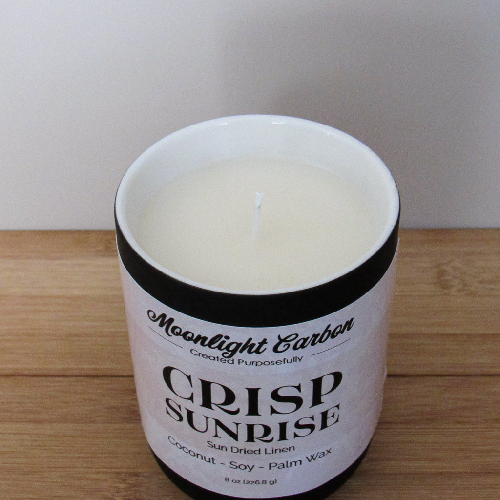 Candle in a white container with 'Moonlight Carbon' branding on a wooden surface. Zoomed in view into  top of candle showing coconut, soy palm wax blend and cotton wick